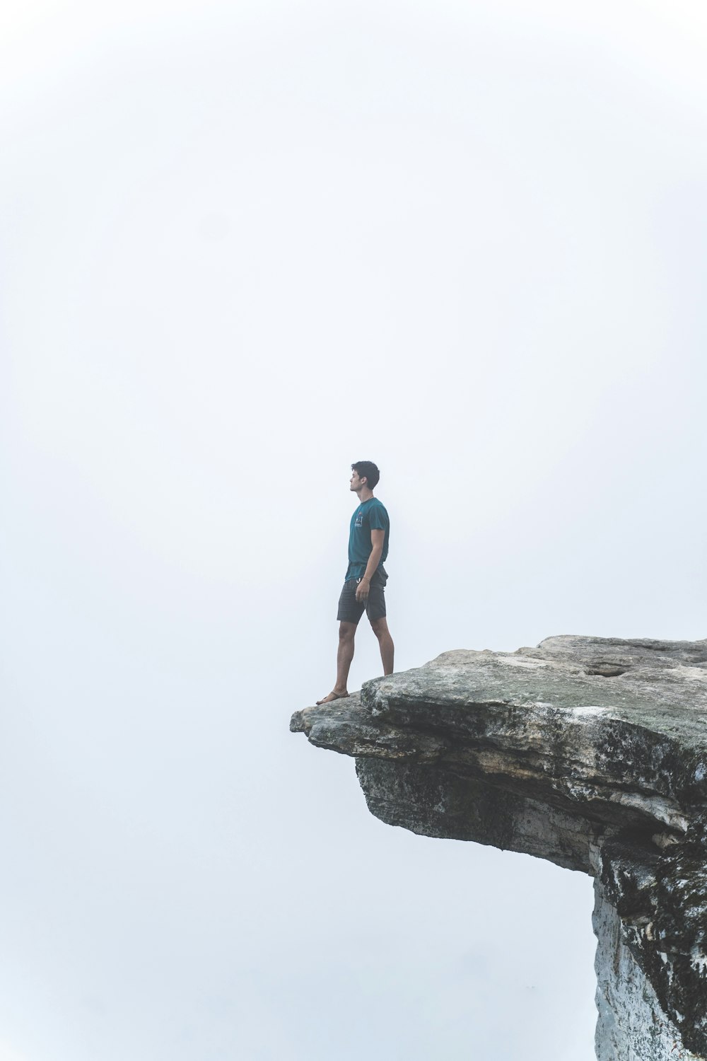 man in blue t-shirt standing on cliff