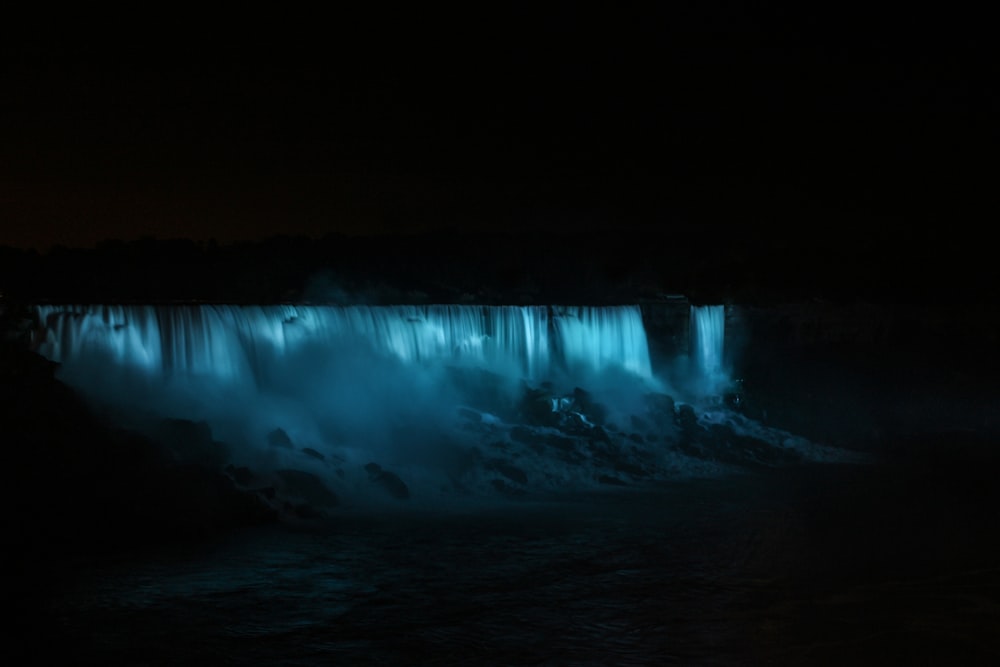a large waterfall is lit up at night