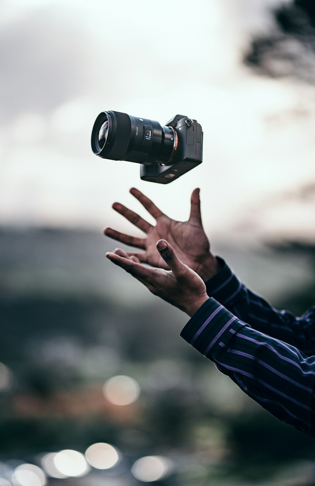 man wearing blue dress shirt catching black DSLR camera