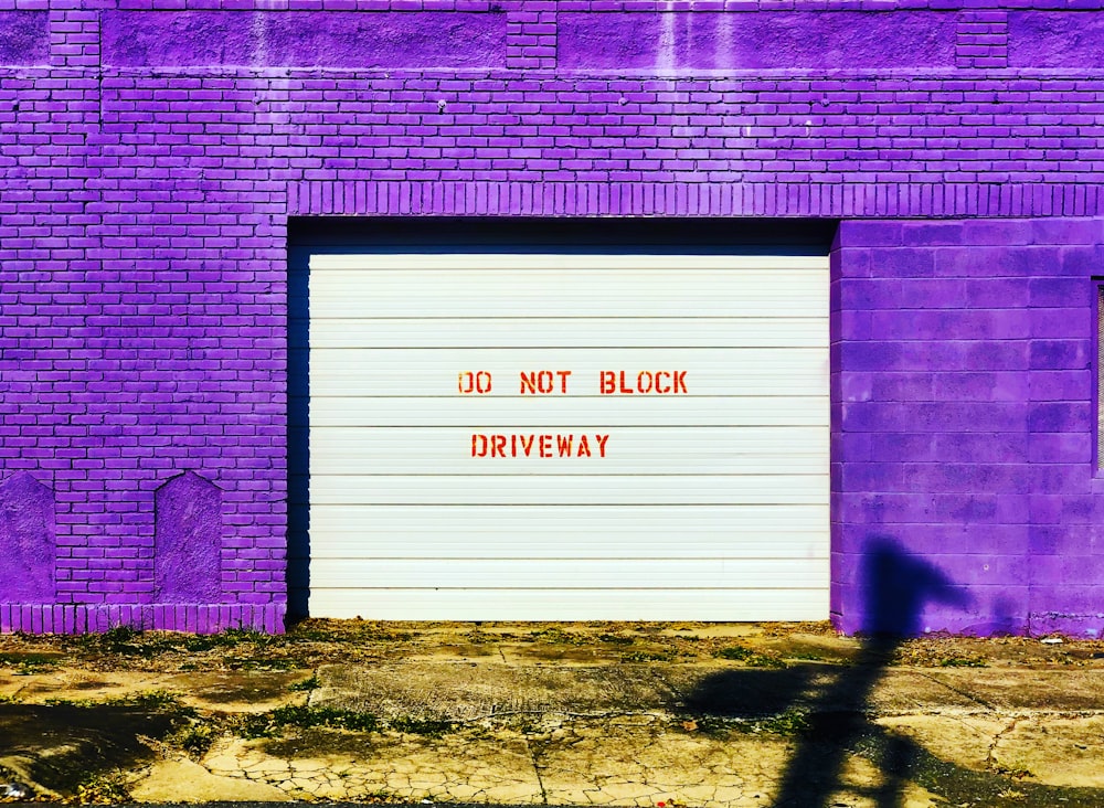 a purple brick building with a white garage door