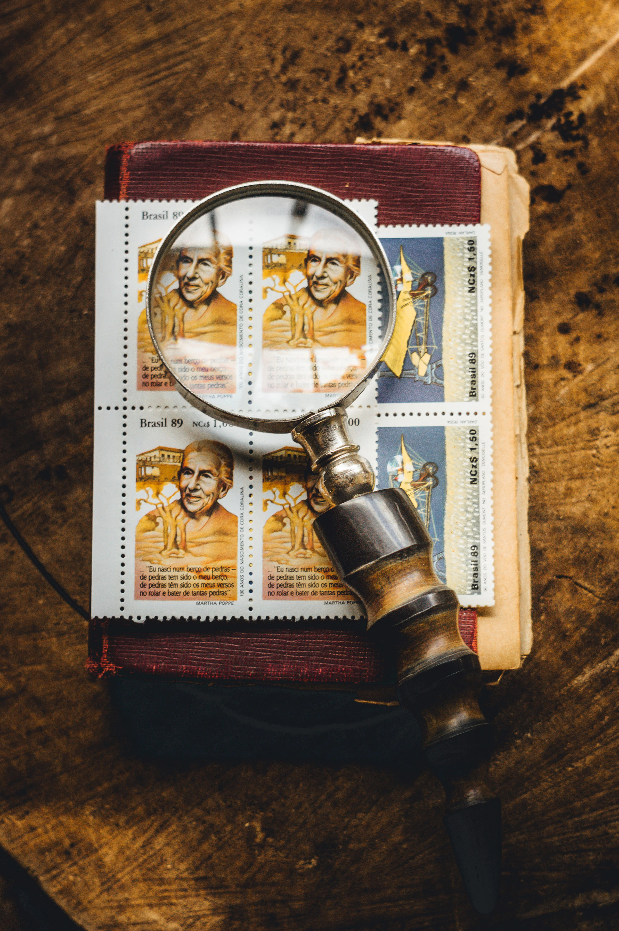 Magnifying glass resting on an old book and historic stamps