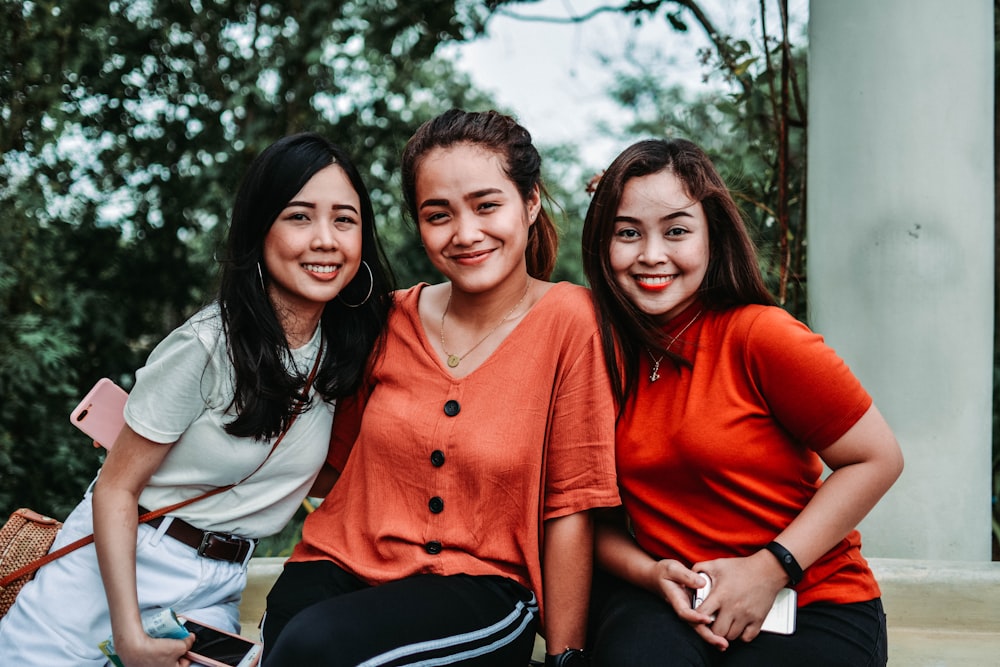 Três mulheres sorridentes perto da árvore