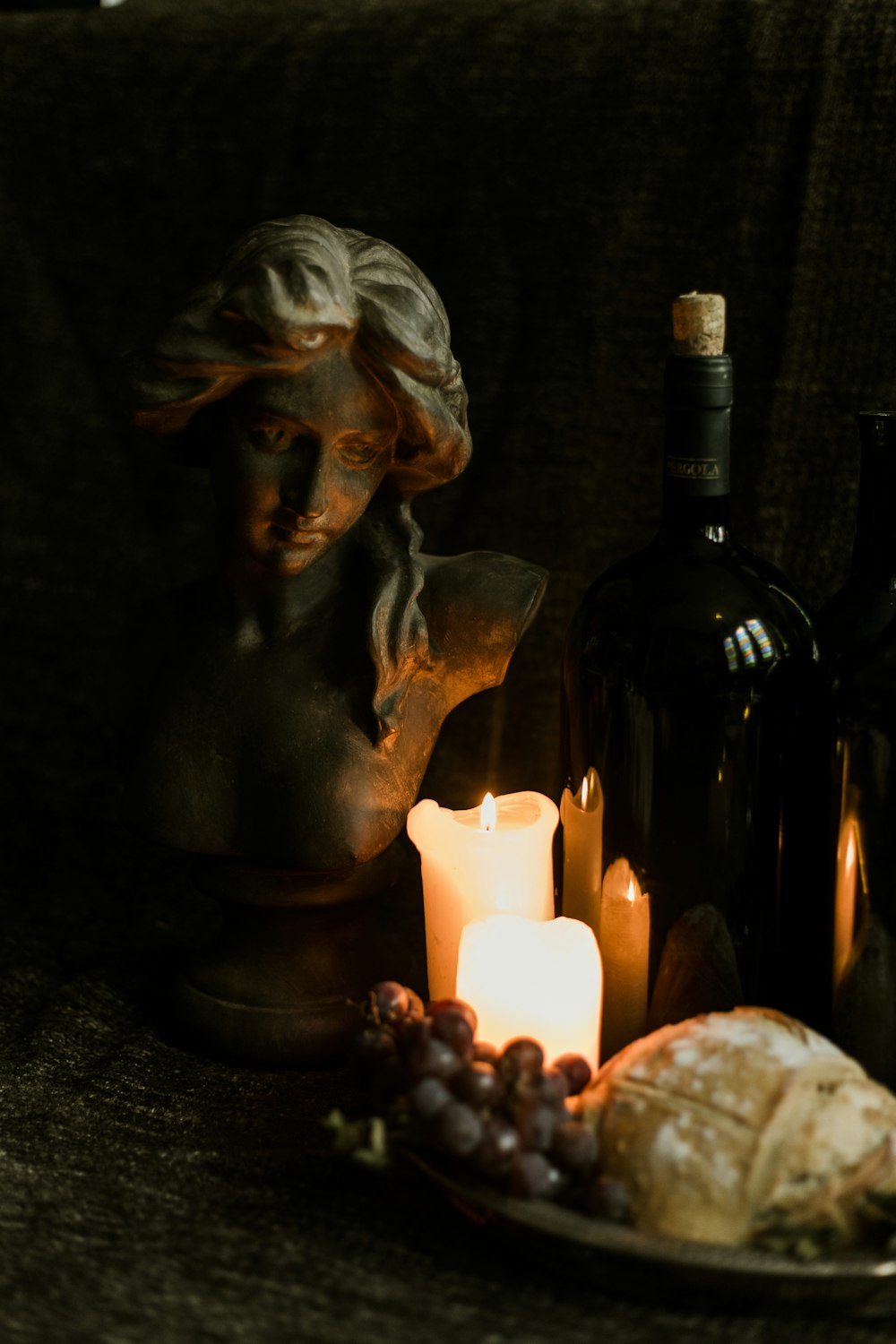 lit candles beside female bust