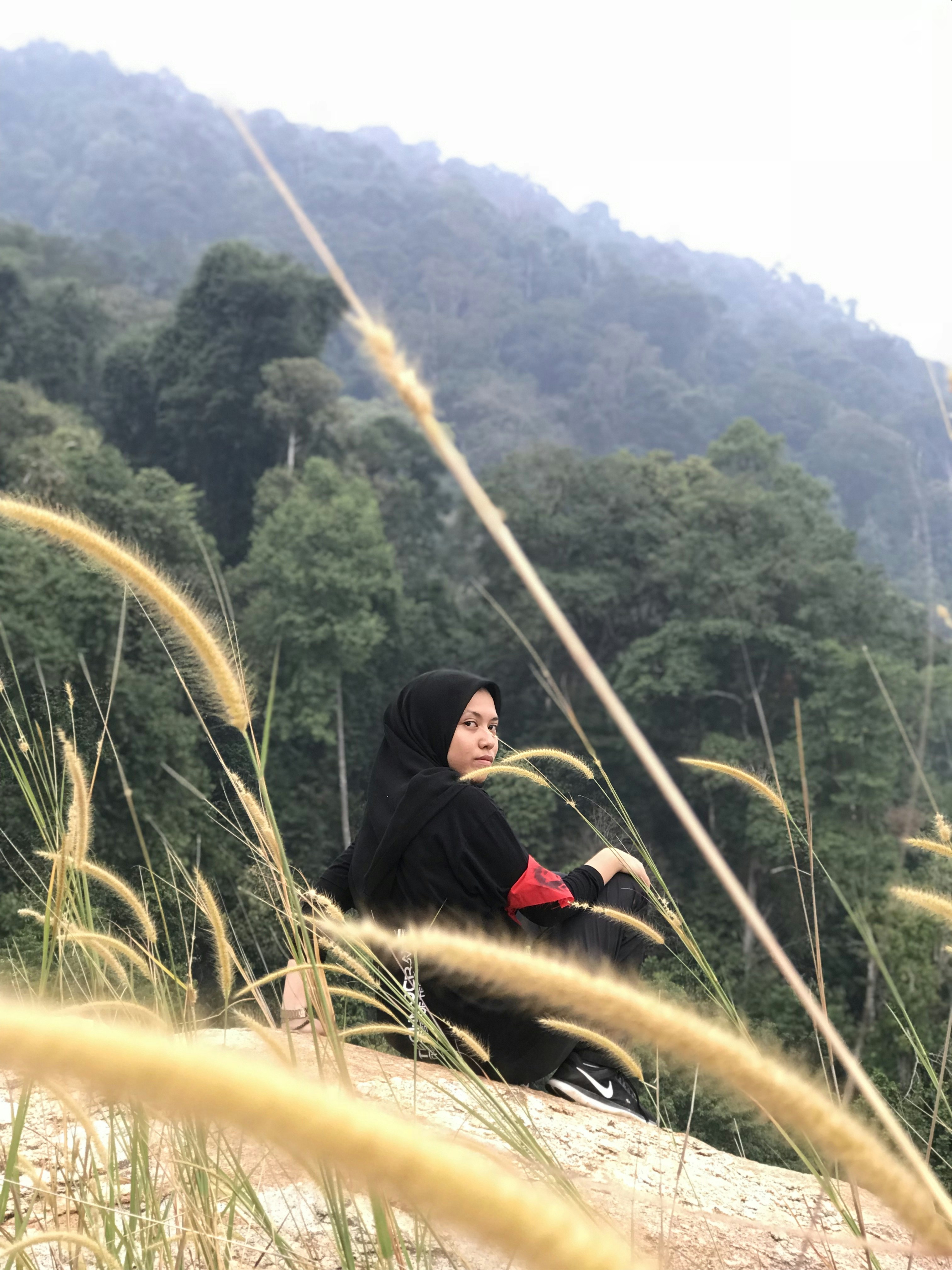 Wanita duduk mengenakan jilbab hitam di siang hari