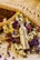 A silver bottle of Montale Paris Vanilla Absolu perfume is surrounded by a colorful array of dried flowers, including purple, yellow, and white blossoms. The scene includes a woven wicker or straw mat positioned behind the bottle and flowers, adding a rustic and natural feel.