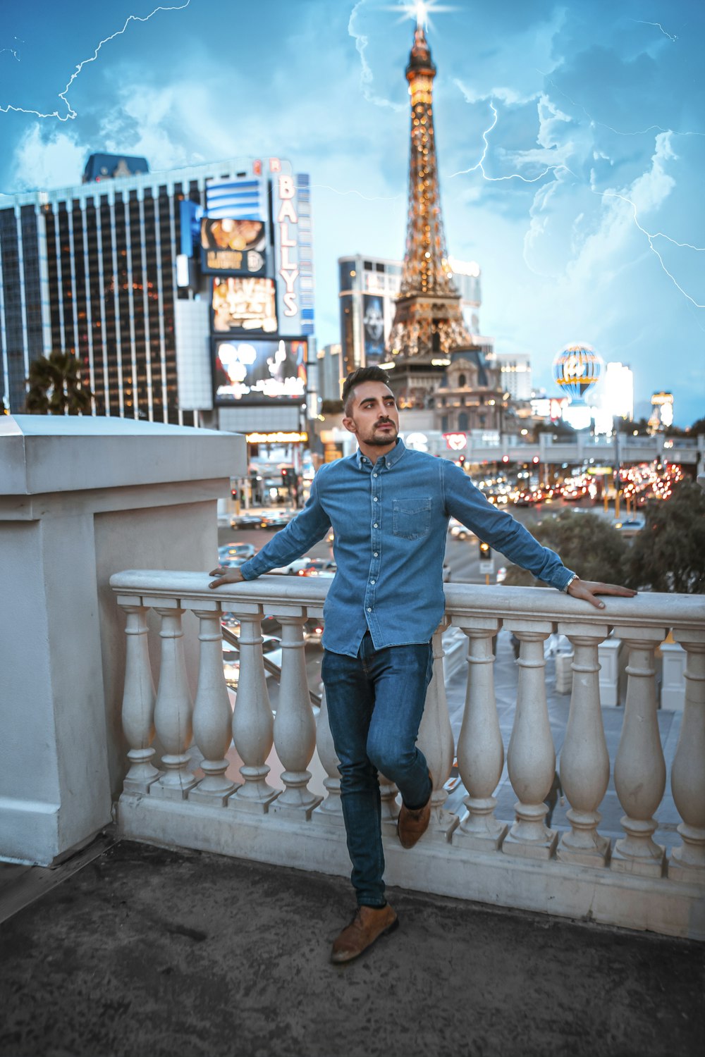 man in dress shirt and blue jeans leaning on balustrade