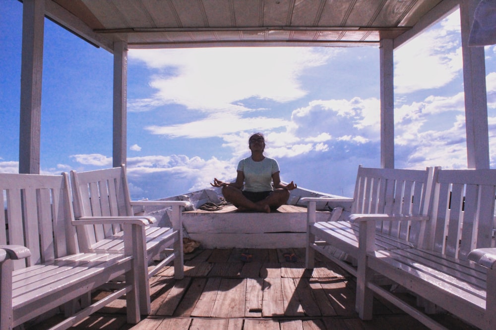 persona meditando frente a bancos de madera