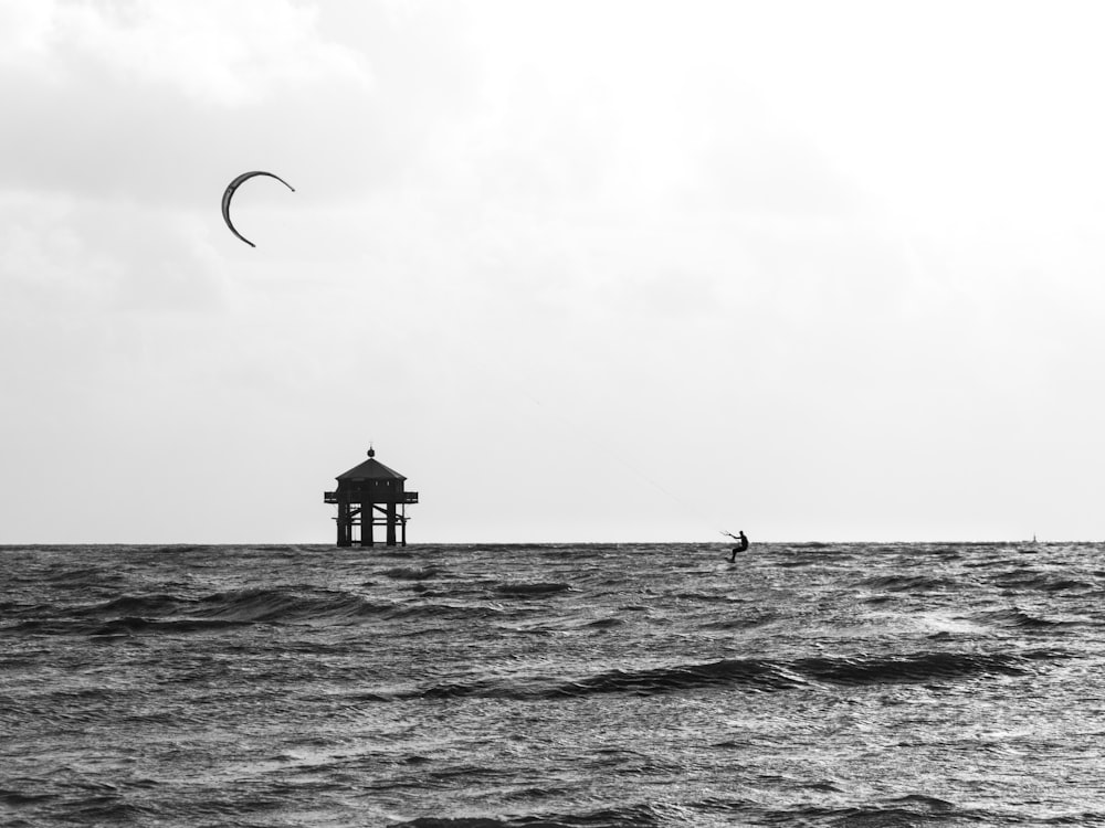 grayscale photo of person surfing on sea