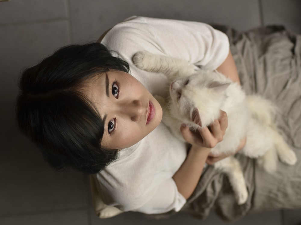 woman wearing white shirt carrying white cat