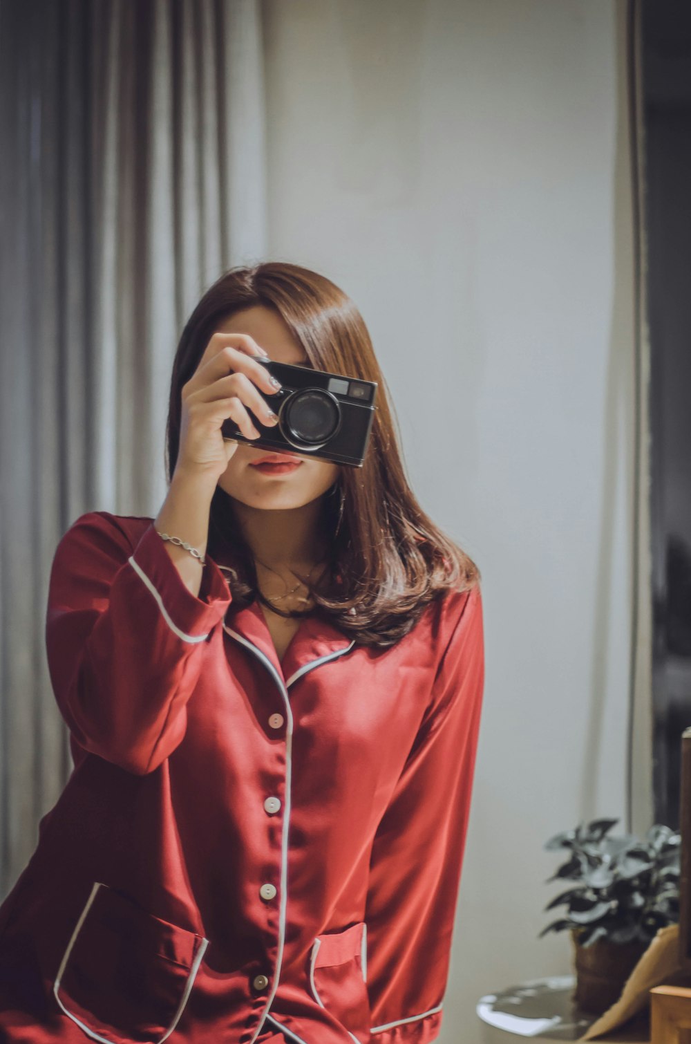 woman holding black camera indoors