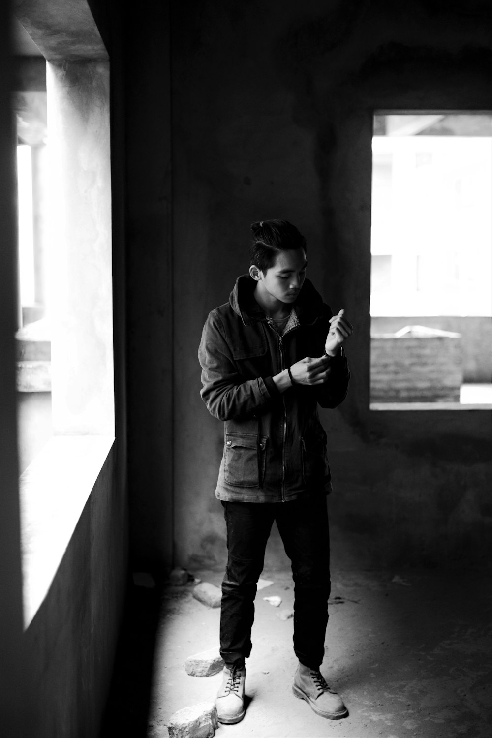 grayscale photography of man standing beside wall