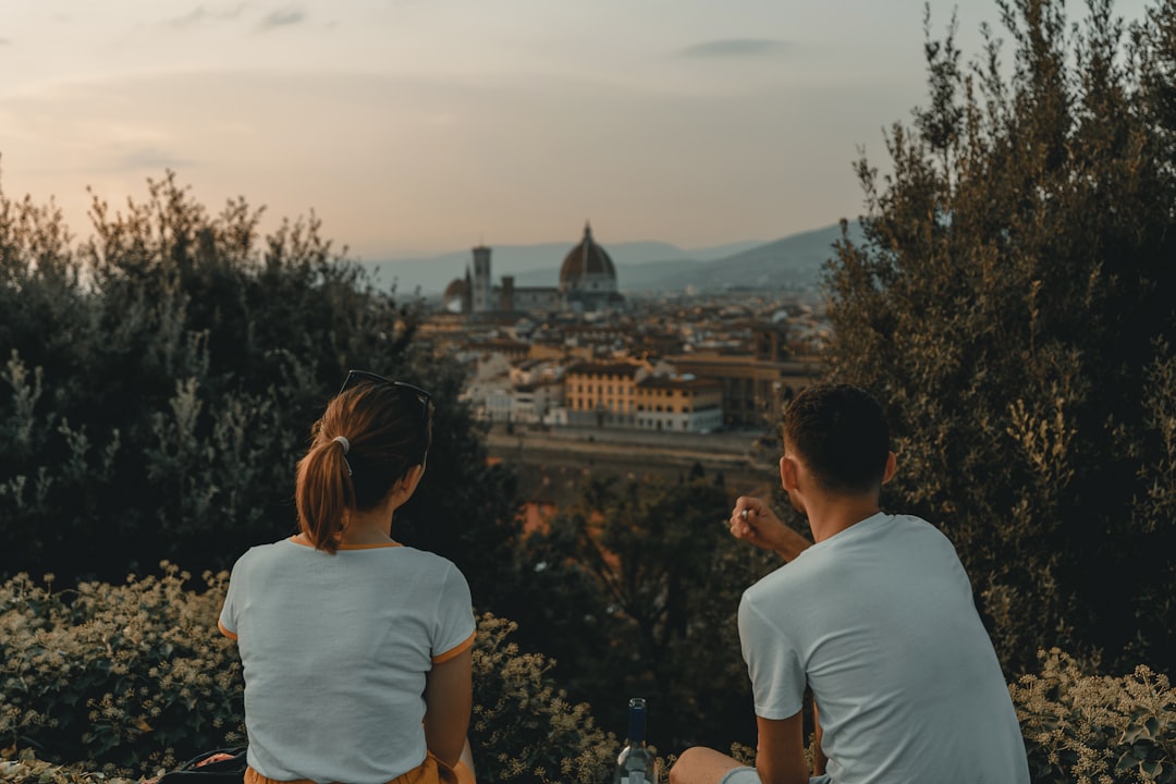 woman and man wearing white shirt while sitting near green trees during daytime