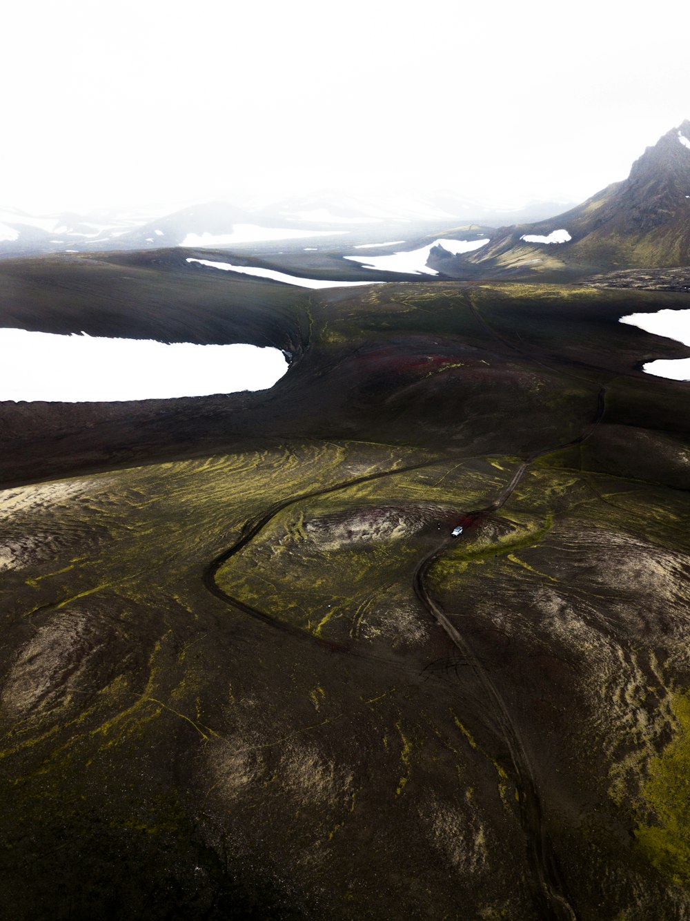 an aerial view of a grassy area with mountains in the background