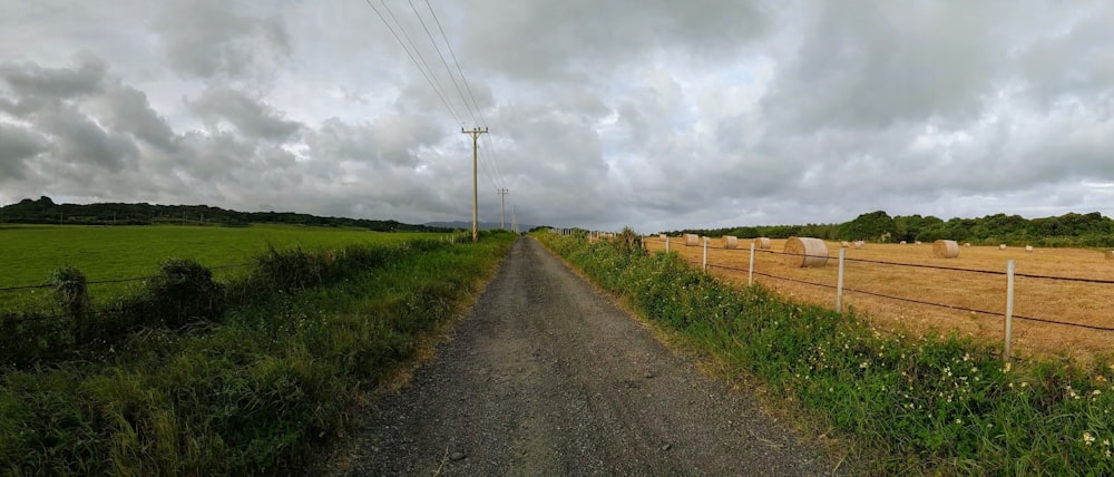 a dirt road with hay bales on the side of it