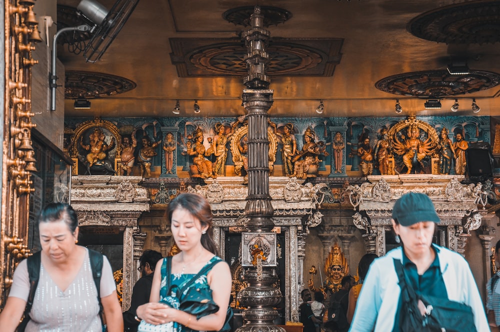 three women walking near Buddha statues