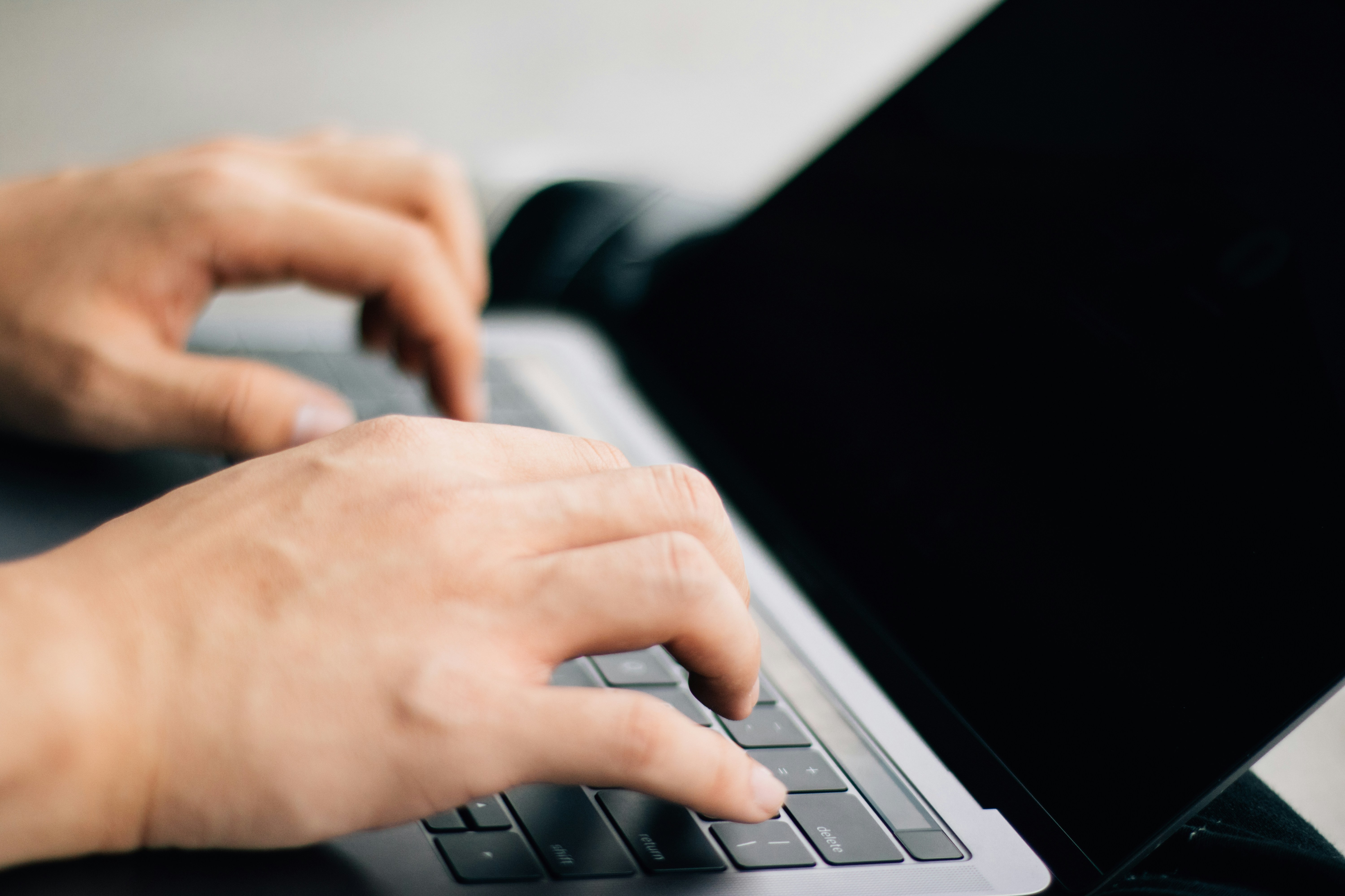 Writer using hands to type on macbook laptop