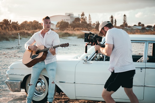 man carrying guitar near car