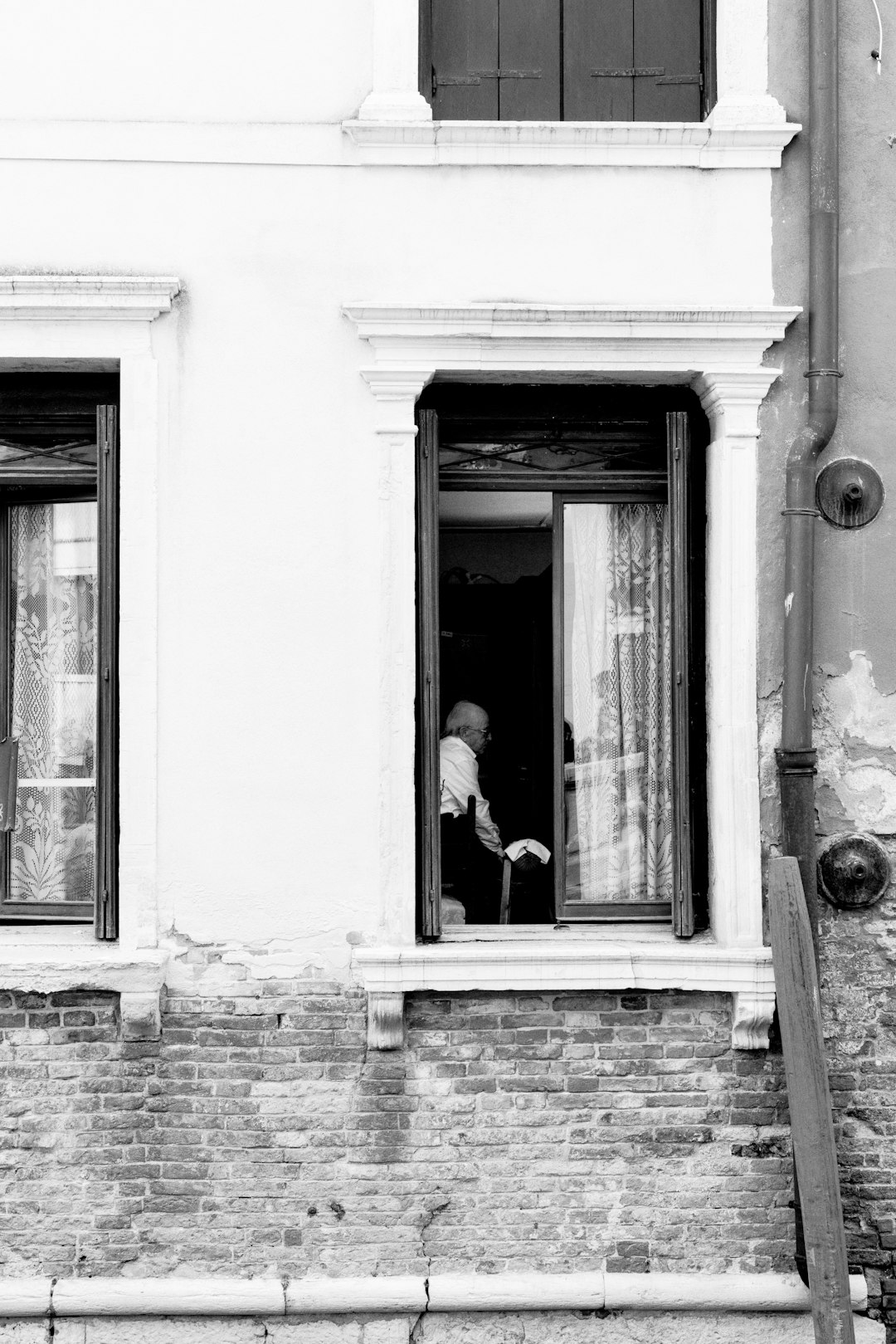 grayscale photo of man by the window