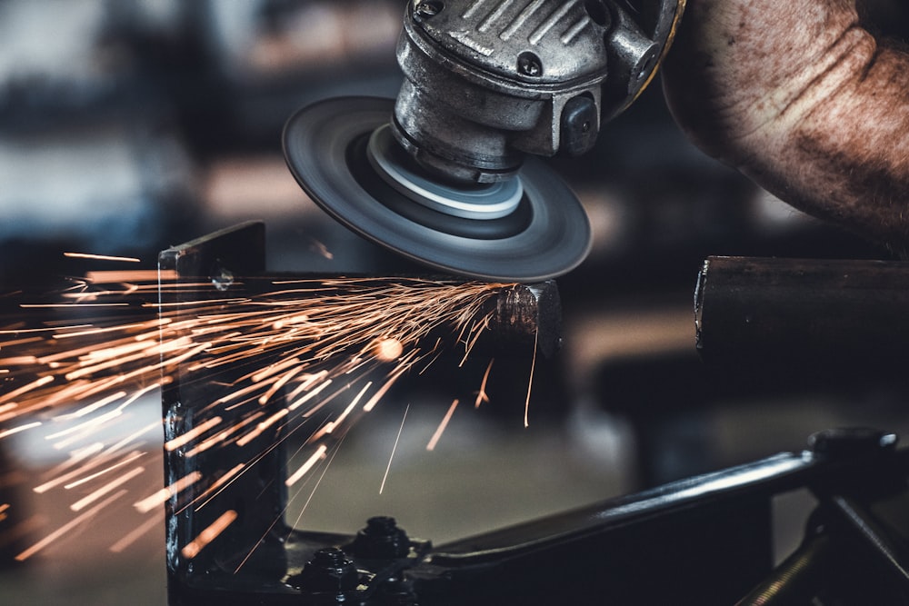 shallow focus photo of person using angle grinder