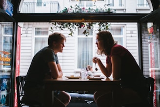 shallow focus photo of two men sitting in front of blakc wooden table