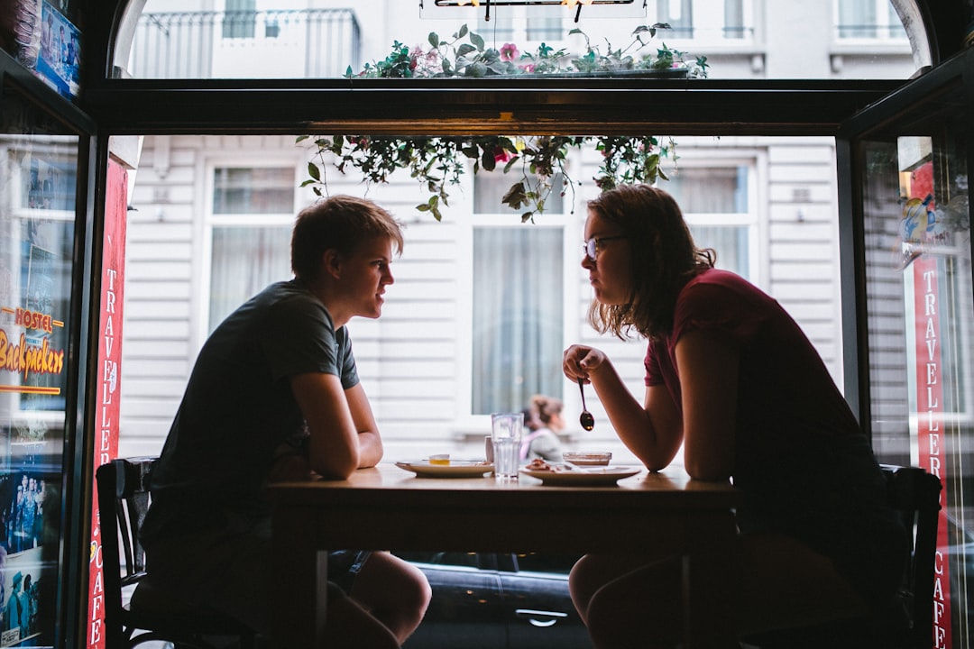 shallow focus photo of two men sitting in front of blakc wooden table