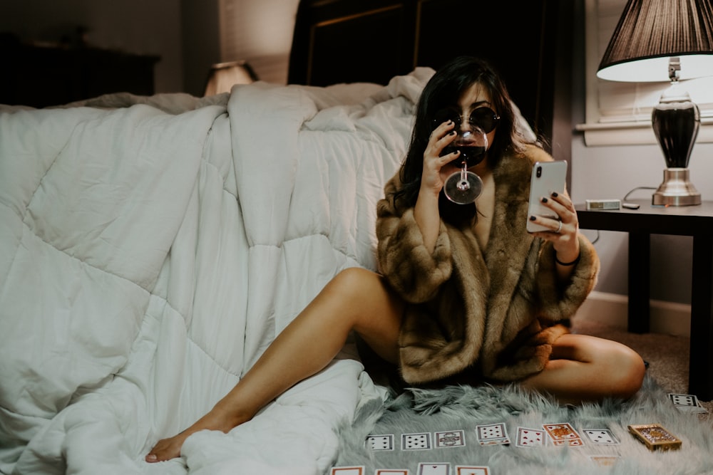 woman in brown coat holding white iPhone