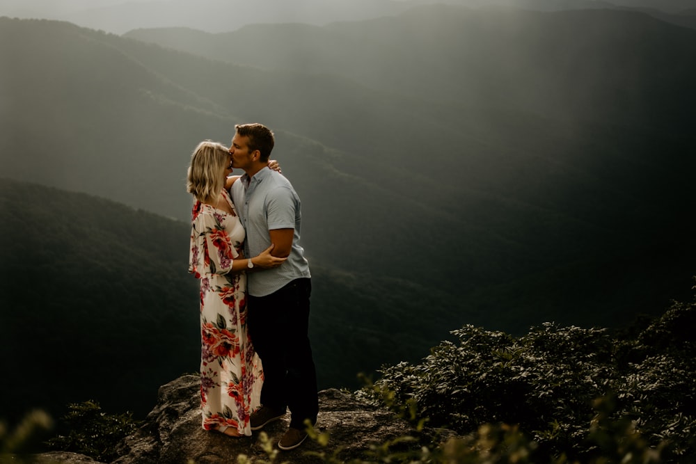 man wearing gray polo shirt kissing a woman in forehead and woman wearing white and red floral dress