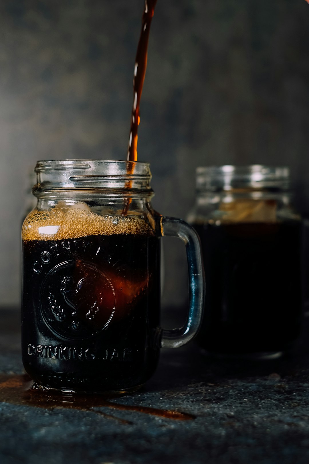 Pouring Cold Brew Coffee into Glass Rustic Earthy Background