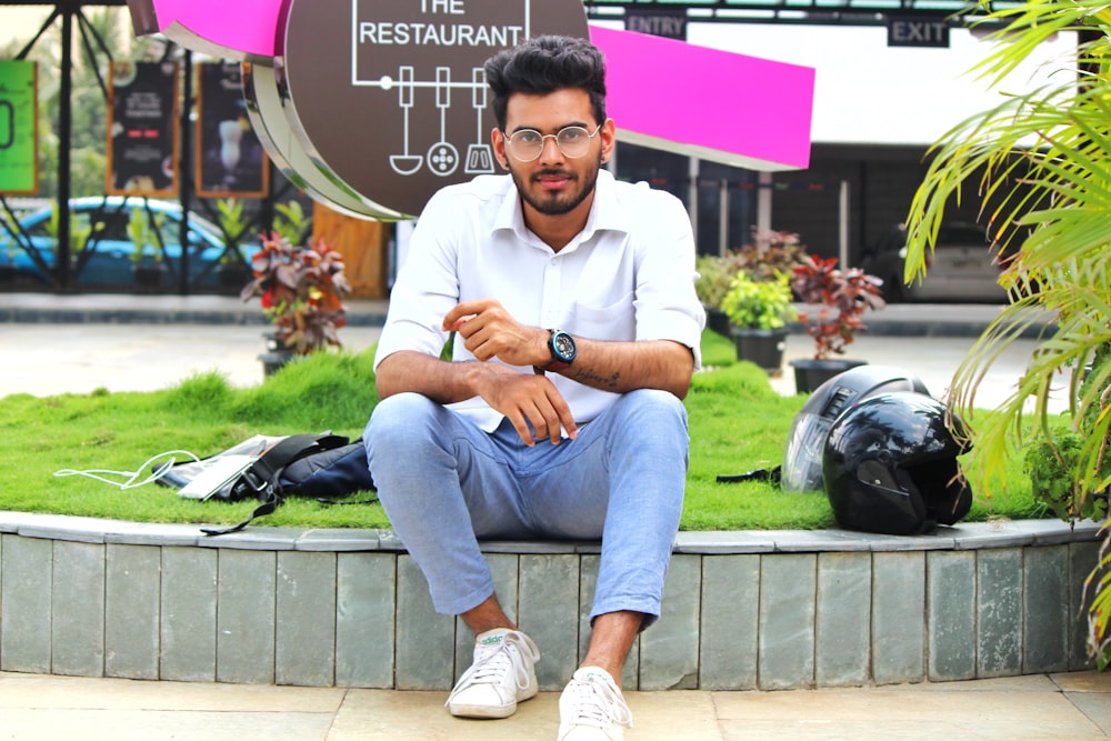 man sits beside black helmet near restaurant signage