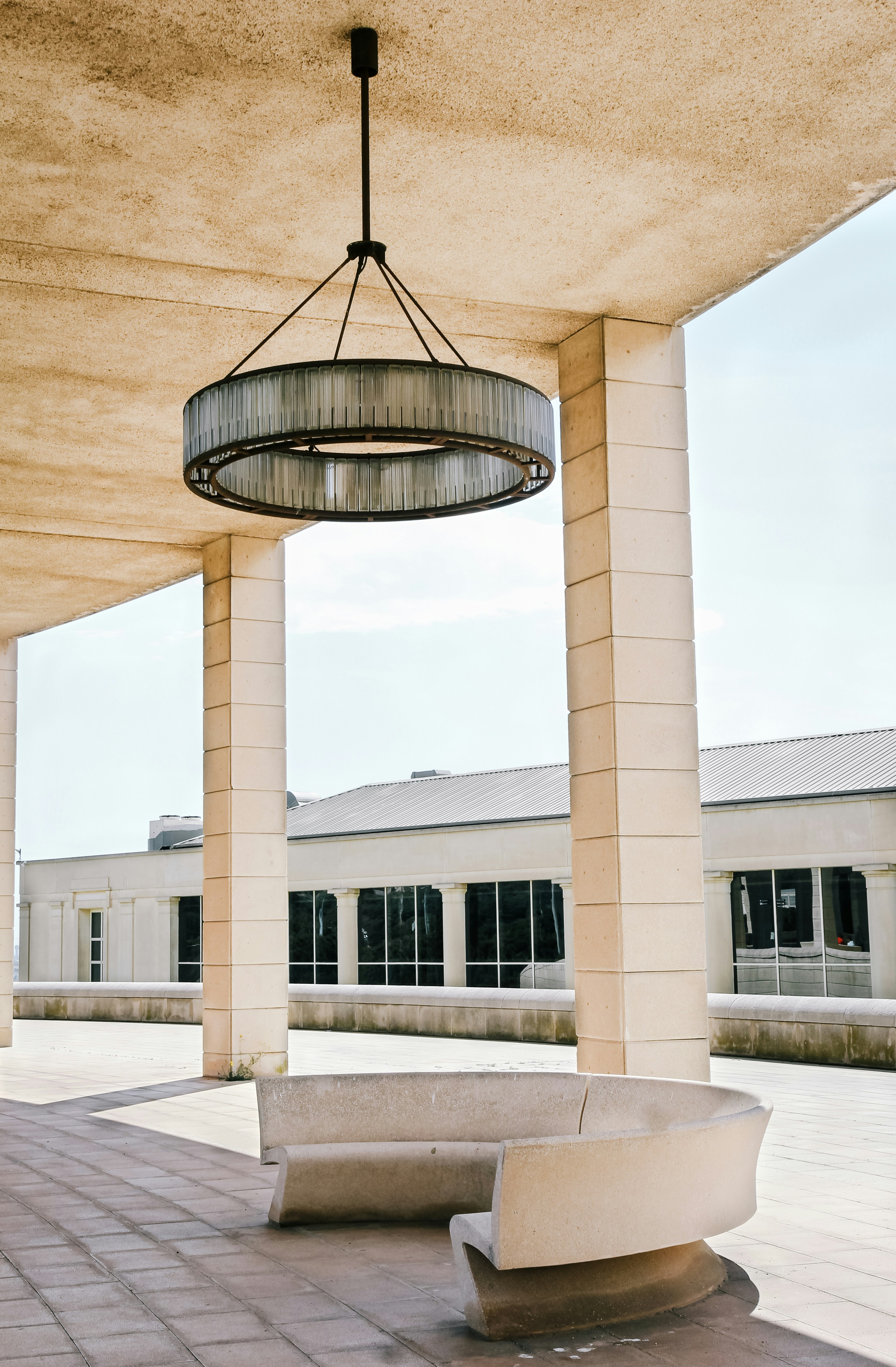 A concrete bench under a chandelier on a bright sunny day