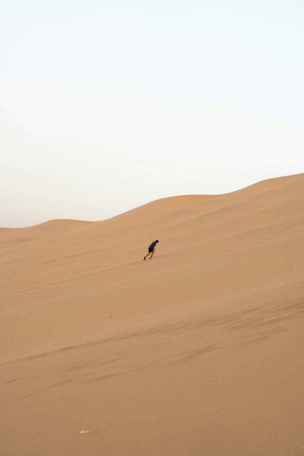 hombre escalando dunas de arena
