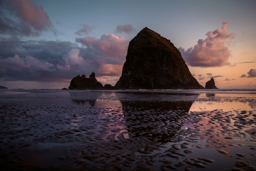 reflection of a mountain on seashore during golden hour