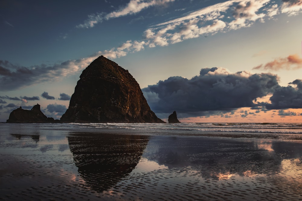 reflection of a mountain on beach shore during daytime