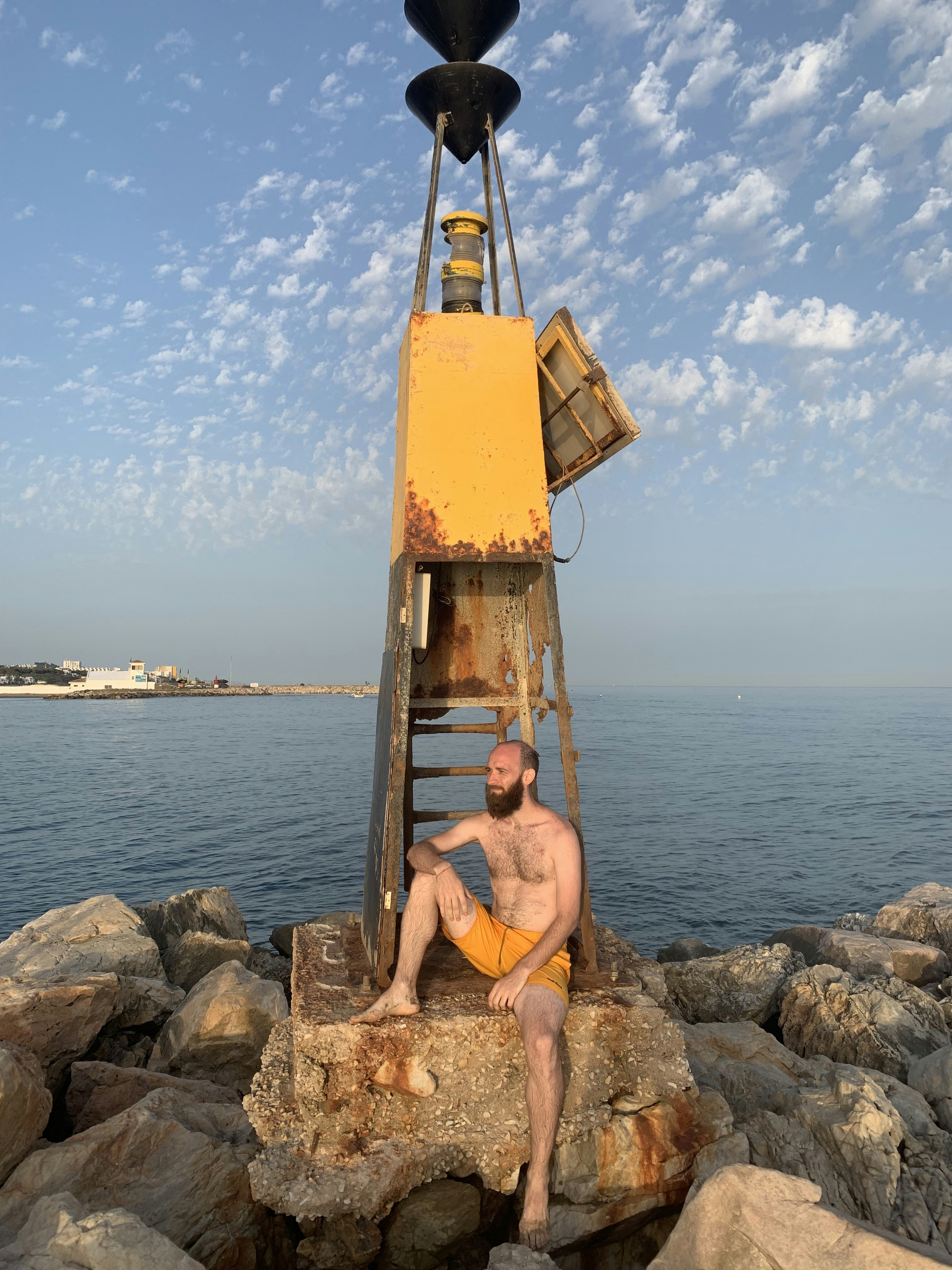 man sitting on a metal tower by the sea