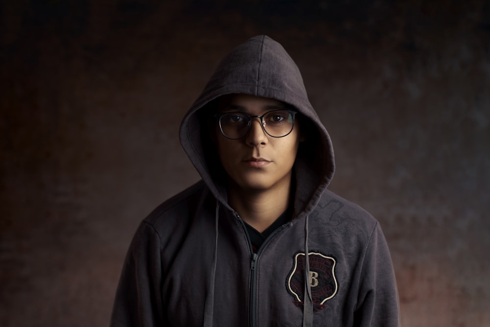 person wearing eyeglasses and gray zip-up hoodie