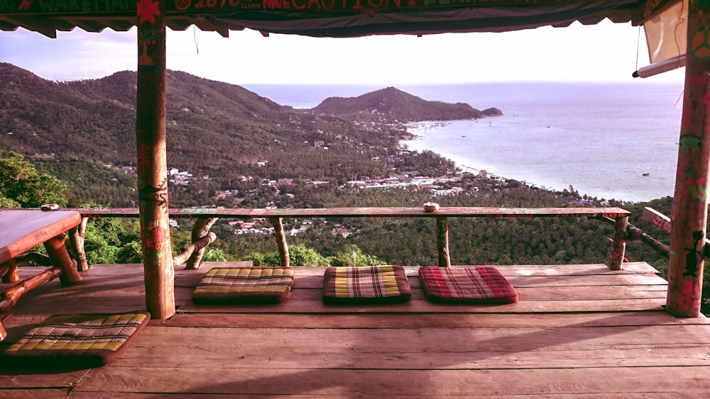 tavolo di legno marrone vicino alle ringhiere che osservano la montagna e il mare blu durante il giorno