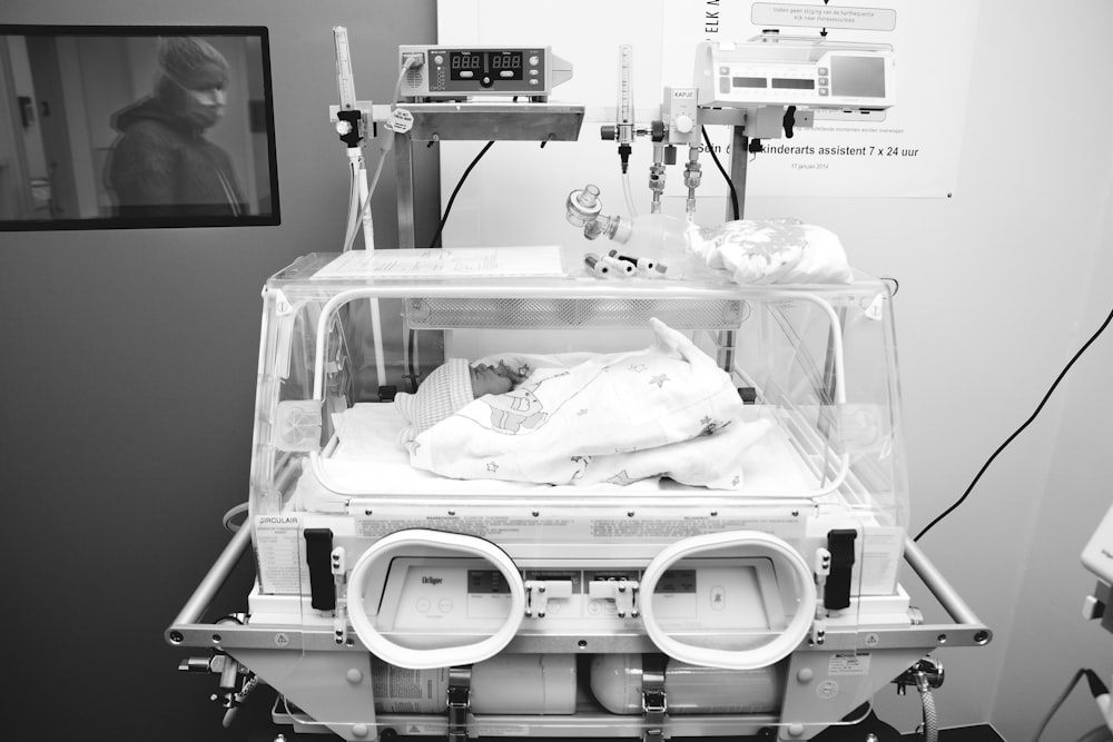 grayscale photography of baby inside medical equipment