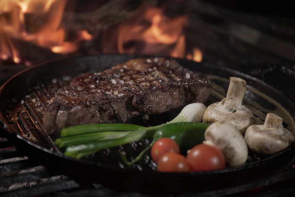 a steak and vegetables cooking on a grill