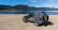 Close-up of a rugged Jeep Wrangler JK on a rocky trail under a bright blue sky.