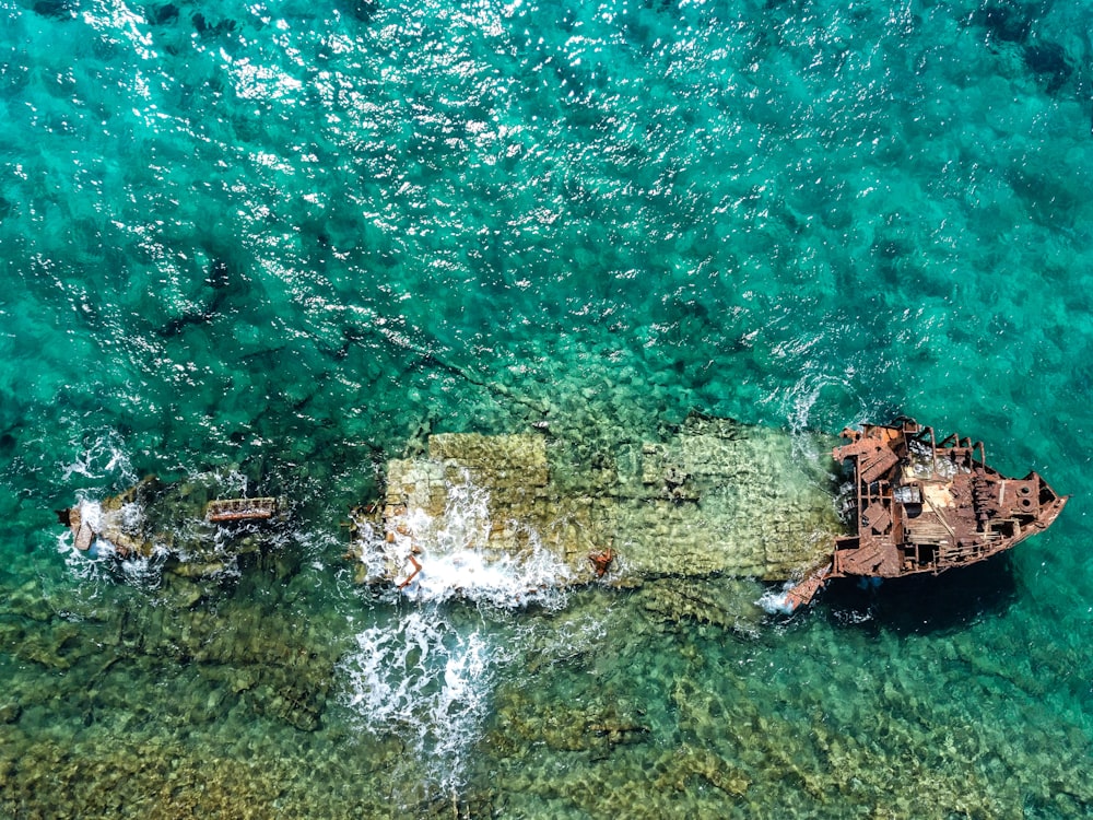 Fotografía aérea de un barco abandonado en un cuerpo de agua durante el día