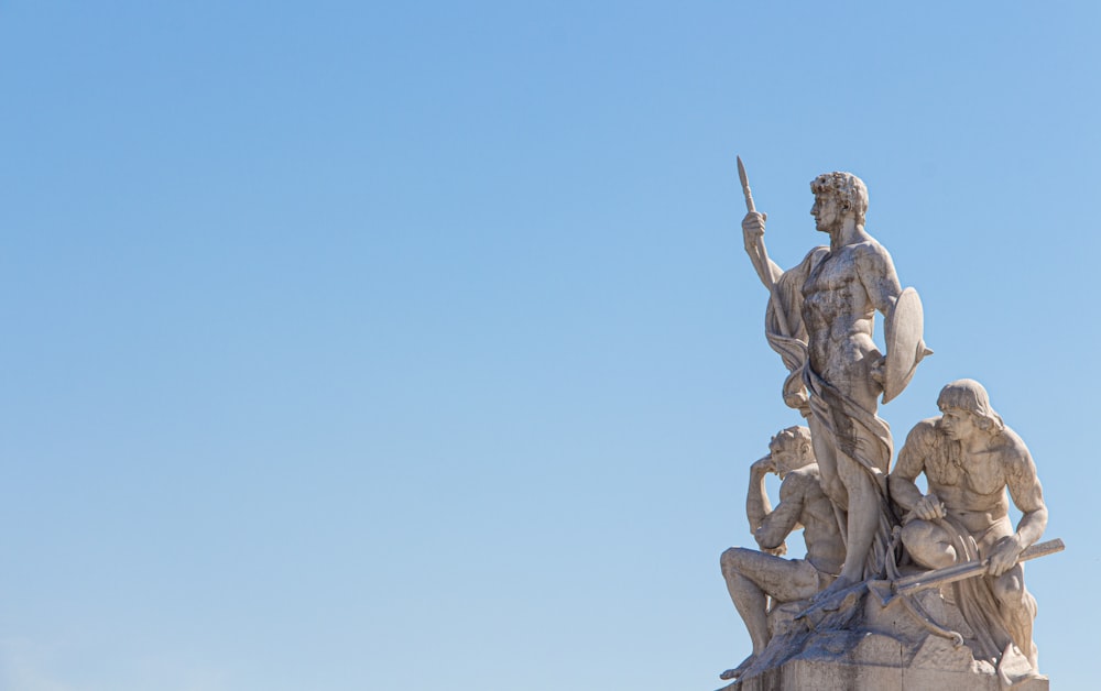 three men holding sword and shield statue