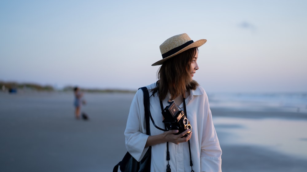a woman standing on a beach holding a camera