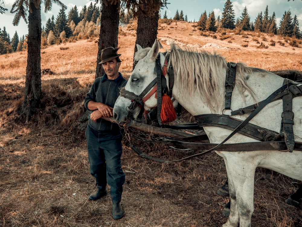 man wearing cowboy costume standing near white horse in field during daytime