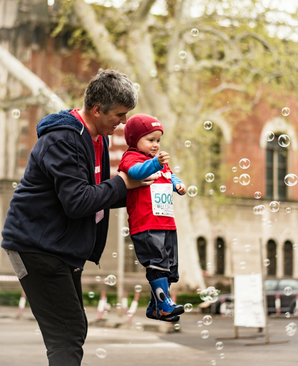 man carrying baby playing bubbles