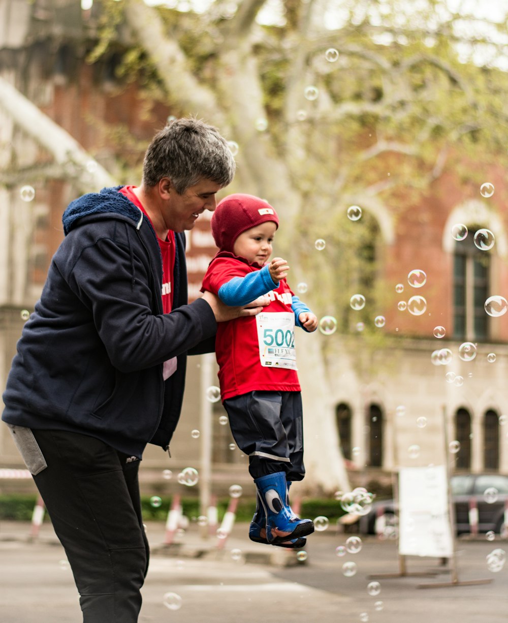 homme portant bébé jouant des bulles