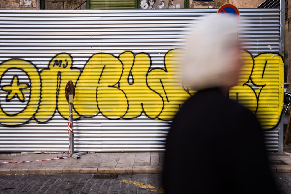 a man walking past a graffiti covered wall