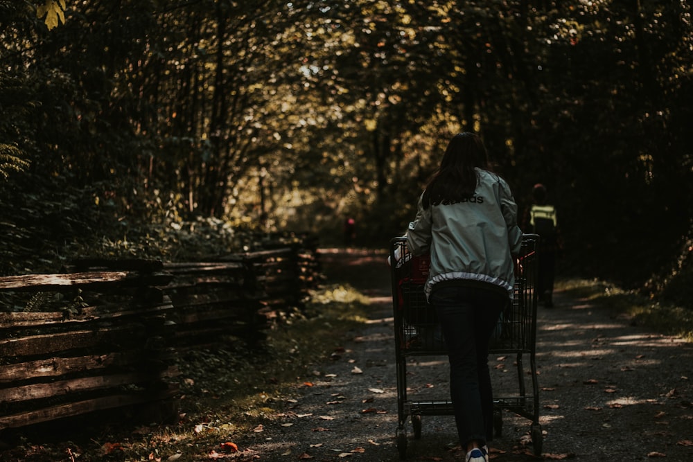 woman pushing cart on dirt road