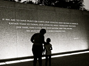 man and woman standing beside gray wall