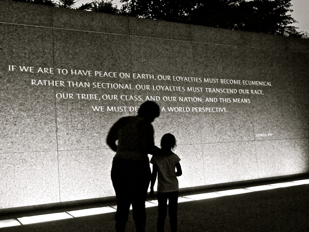 man and woman standing beside gray wall