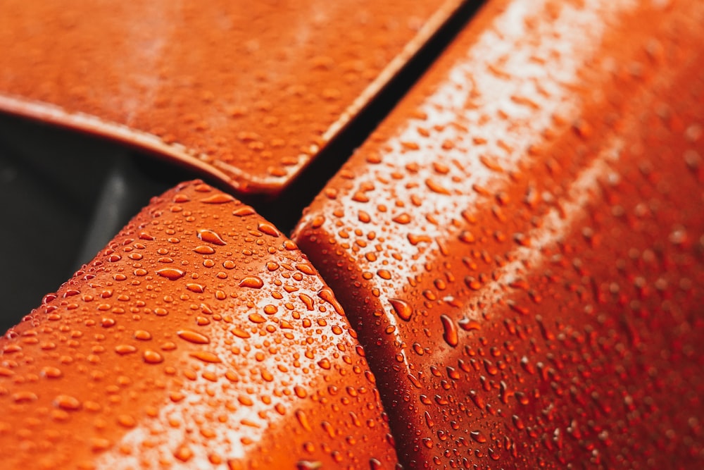 a close up of a red car with water droplets on it